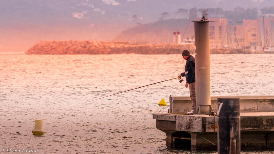Pêcheur à l'extrémité d'un quai au port du Lavandou, mars 2022