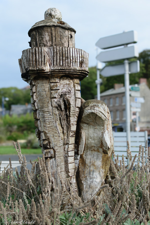 Une statue sur bois représente un dauphin au pied du phare à proximité du kiosque à musique de Saint-Valéry-en-Caux